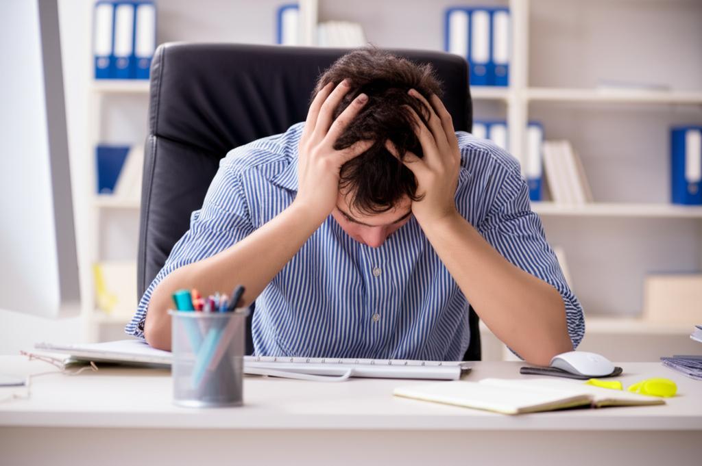 Exhausted office worker sitting at desk, head in hands, looking tired